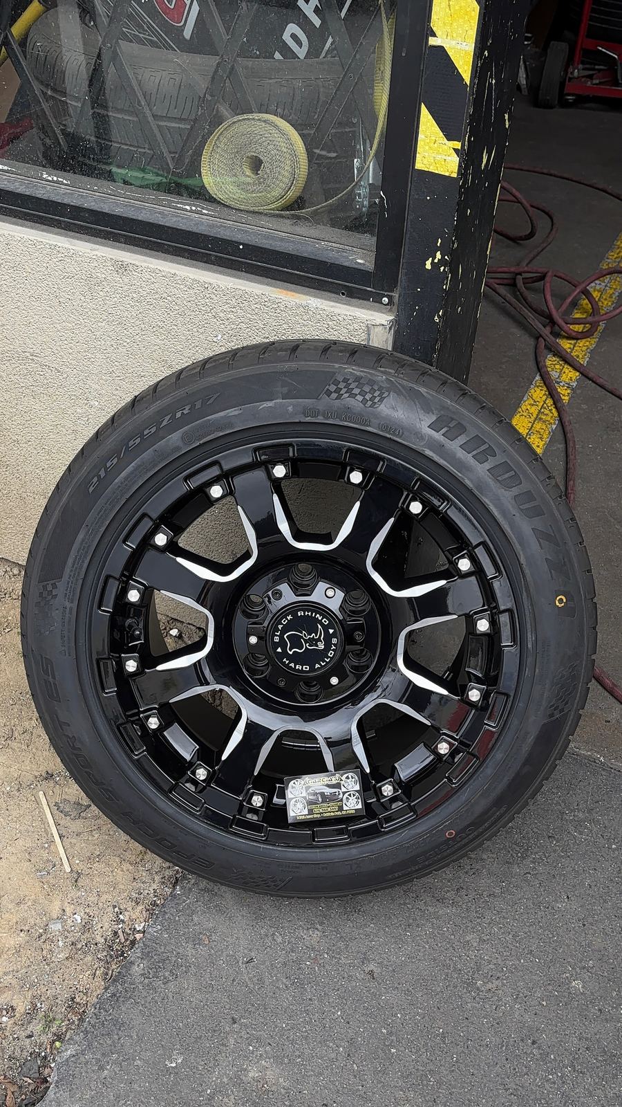Black off-road wheel with milled accents leaning outside the shop